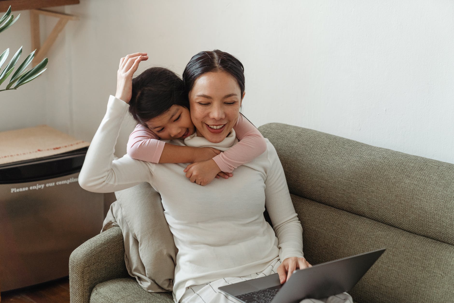 cheerful girl hugging mother on couch