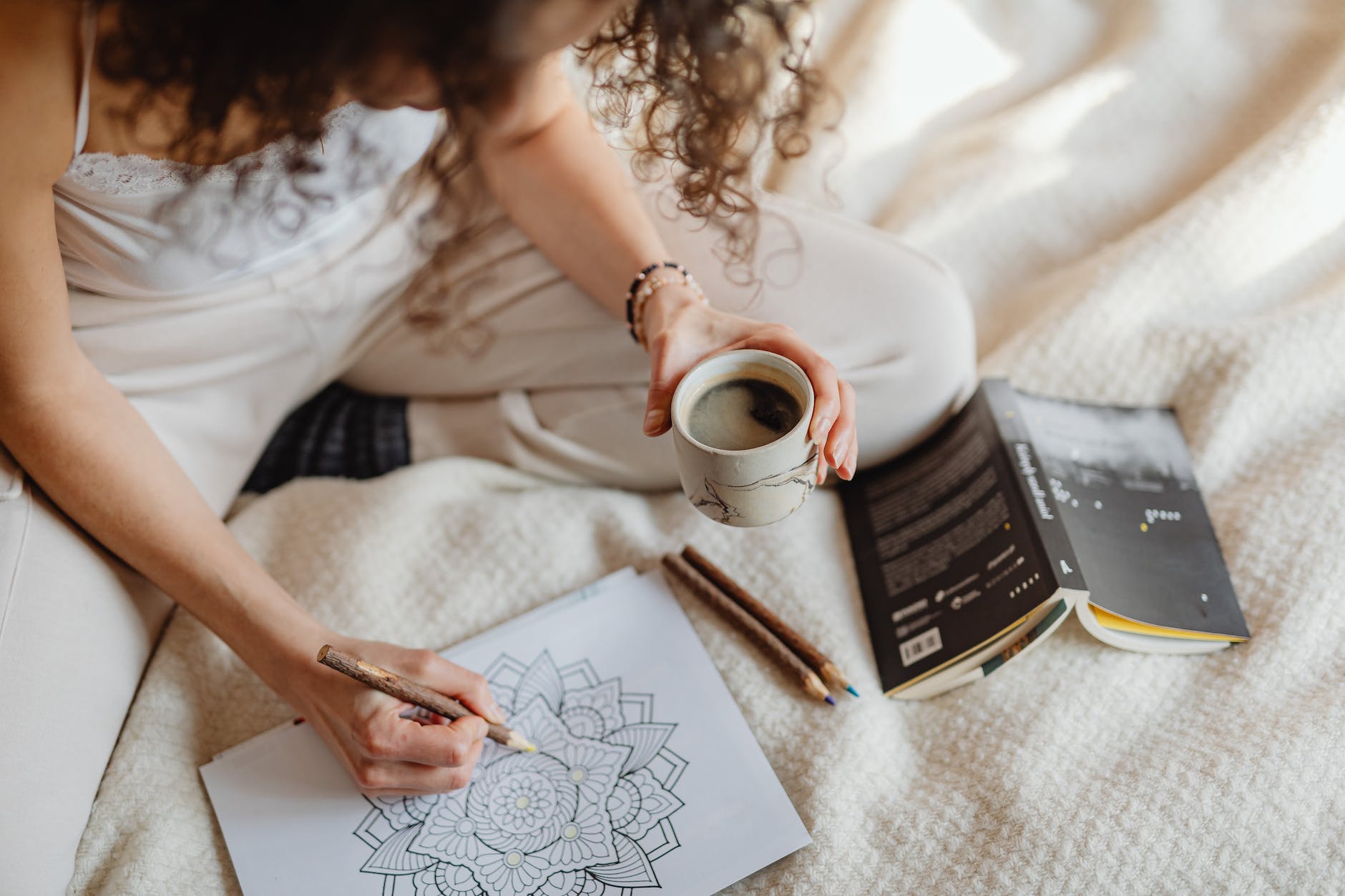 a woman holding a cup of coffee while doing an artwork