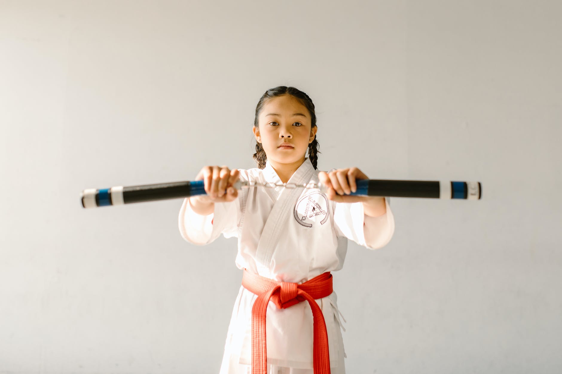 a girl with red belt holding a nunchaku
