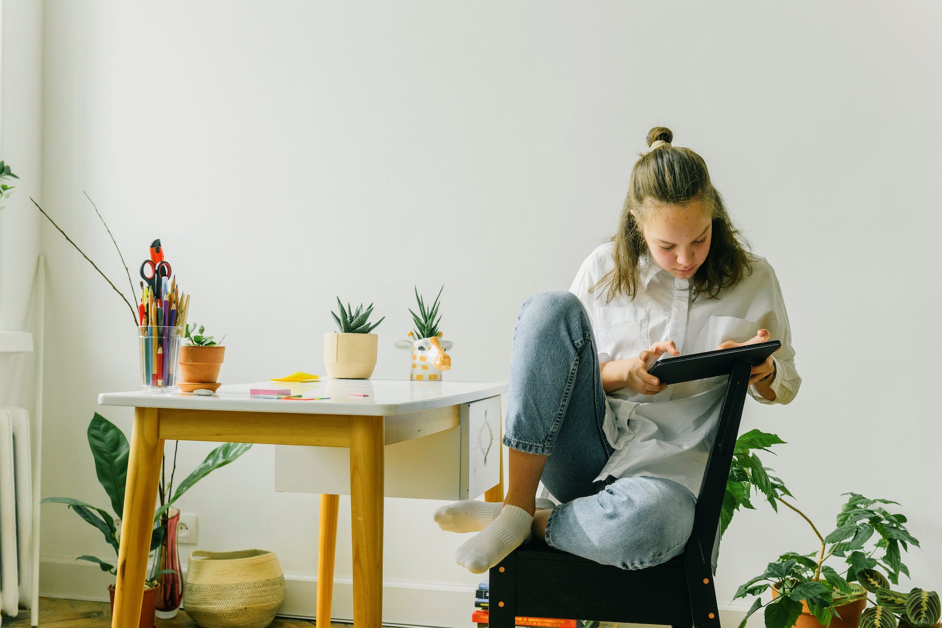 a woman in white long sleeves and denim jeans using her tablet