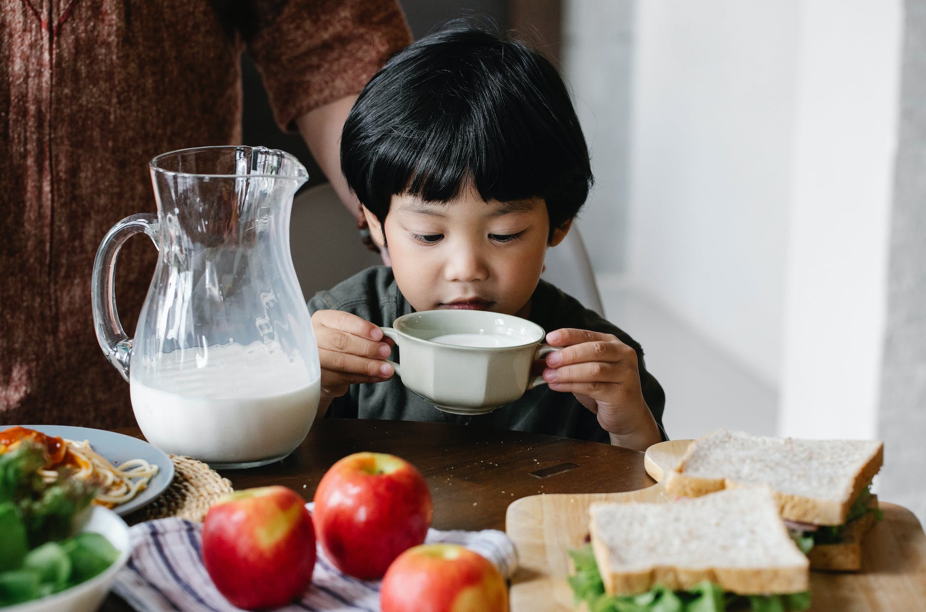 asian boy drinking milk in kitchen
